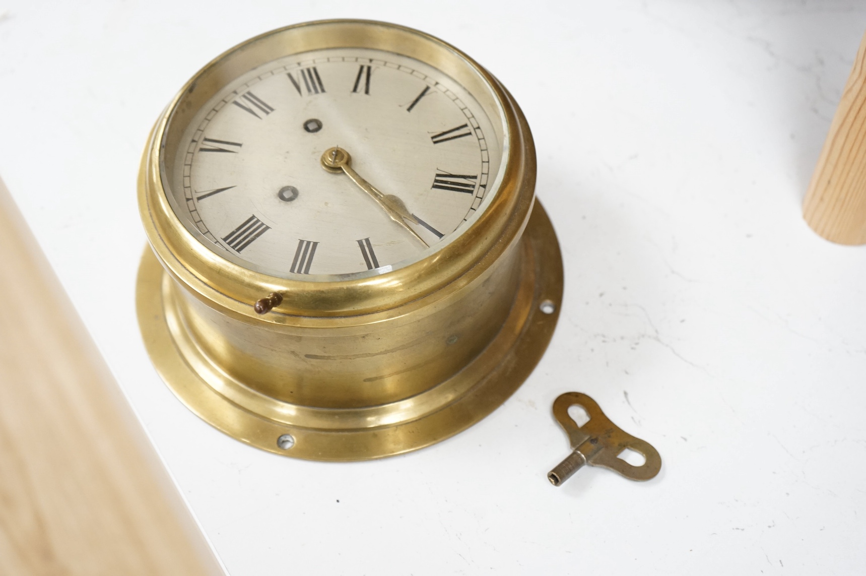 A brass ship's bulkhead timepiece, with key, 21cm in diameter. Condition - good, untested